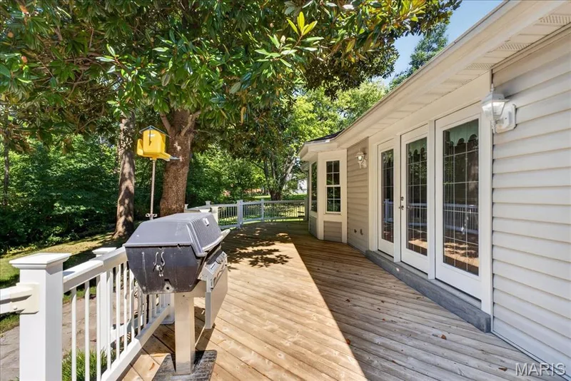 Expansive wood-finish deck with white railing, featuring multiple sets of French doors, bay windows, and siding exterior — 20 Ardennais Road, St Peters, MO 63376