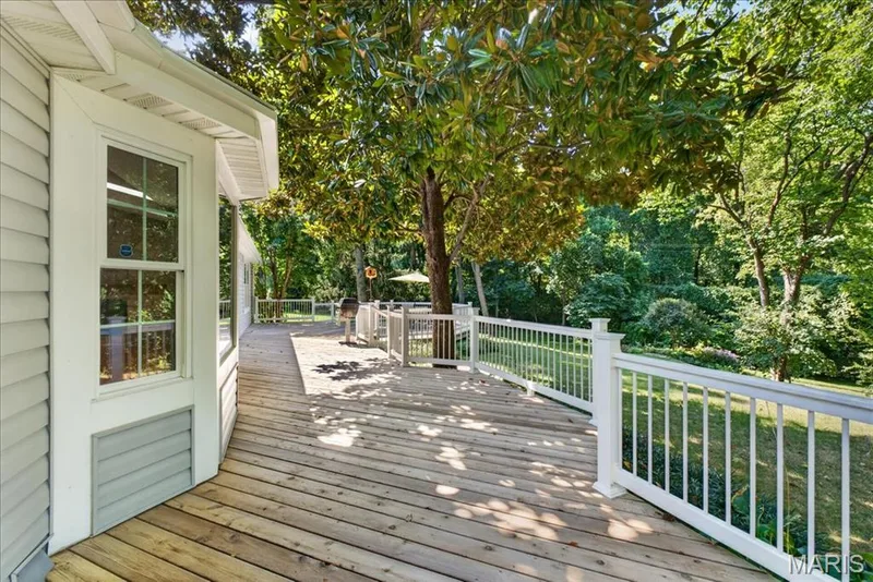 Expansive wood deck with white railings, surrounded by mature trees — 20 Ardennais Road, St Peters, MO 63376