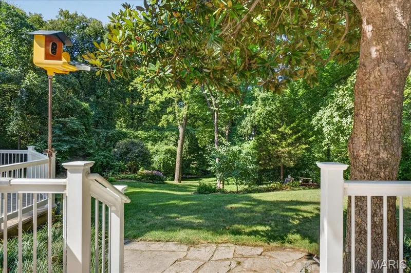 Expansive lawn surrounded by mature trees, featuring a stone path and white railing — 20 Ardennais Road, St Peters, MO 63376