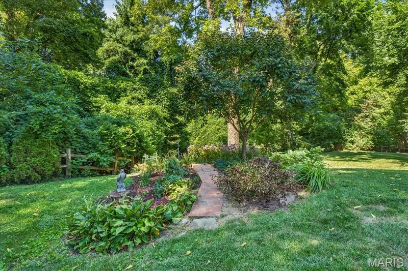 Lush landscaping featuring mature trees and established garden beds — 20 Ardennais Road, St Peters, MO 63376