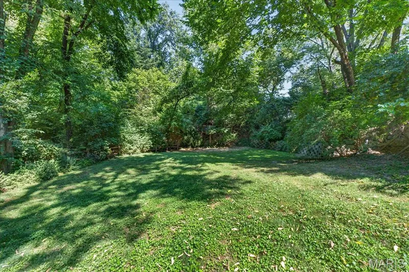 Expansive backyard featuring a manicured lawn, lush trees, and natural landscaping — 20 Ardennais Road, St Peters, MO 63376