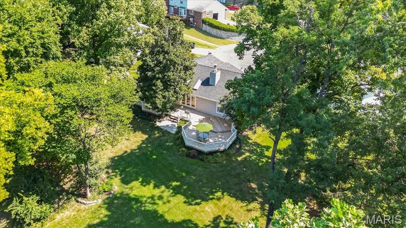 Expansive backyard featuring a large wood-finish deck, lush green lawn, and mature trees — 20 Ardennais Road, St Peters, MO 63376