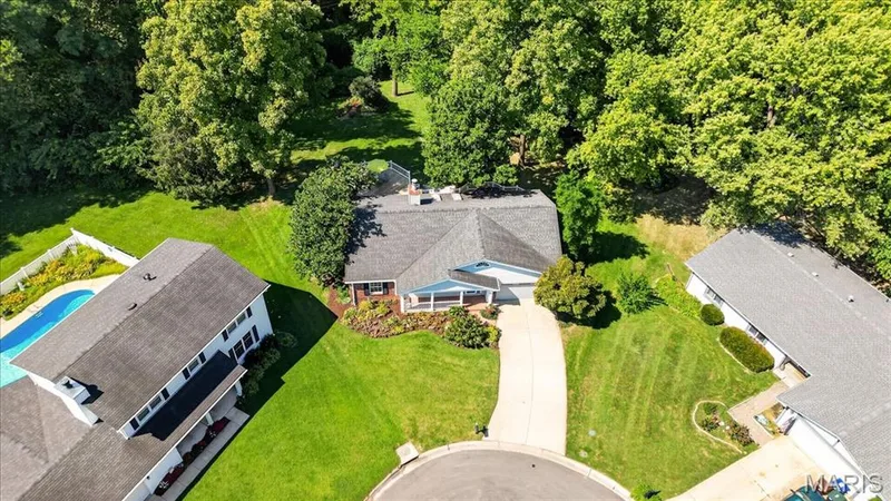 Spacious property featuring a large driveway, established landscaping, and surrounding mature trees — 20 Ardennais Road, St Peters, MO 63376