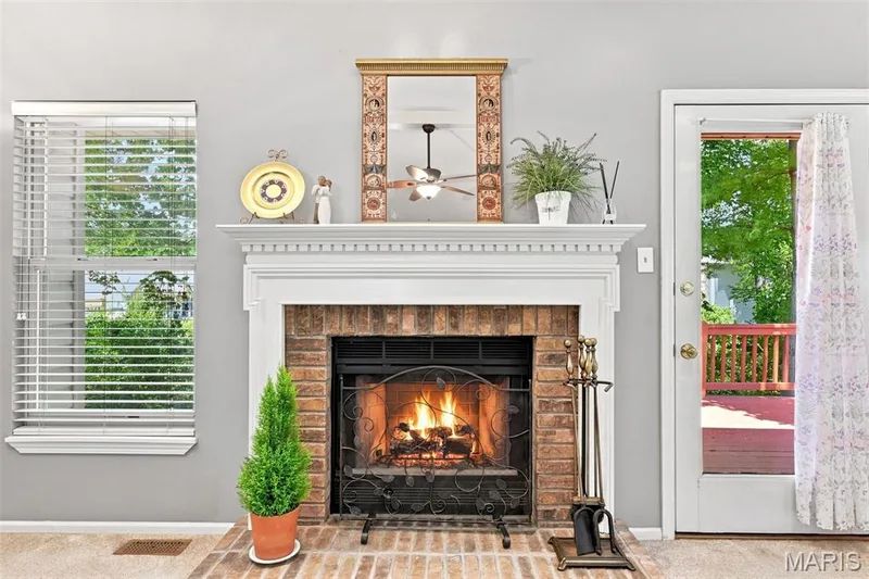 Brick fireplace with a white mantel, hearth, and black fire screen — 55 Treeshade Court, St Peters, MO 63376