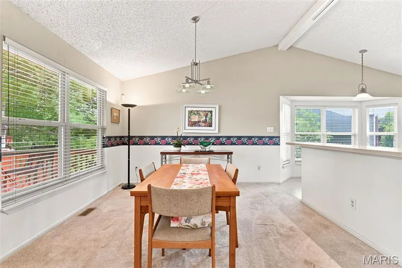 Vaulted ceiling with exposed beams, multiple windows with blinds, recessed bay window, and a built-in half wall with countertop — 55 Treeshade Court, St Peters, MO 63376