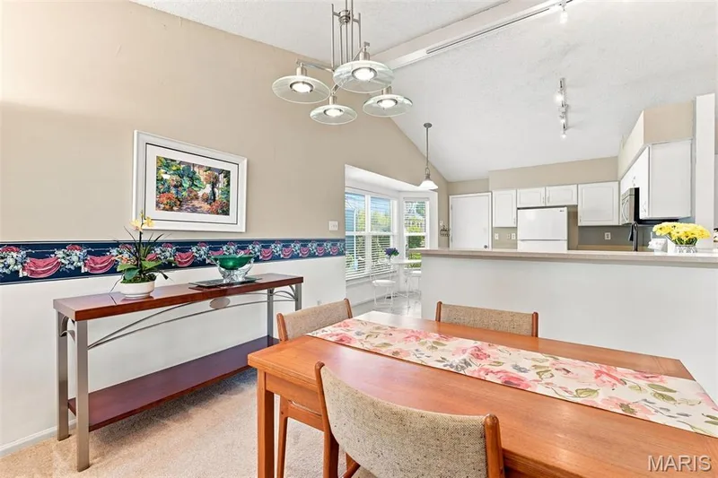 Vaulted ceiling with track lighting, white cabinetry, light-toned countertops, and a bay window — 55 Treeshade Court, St Peters, MO 63376