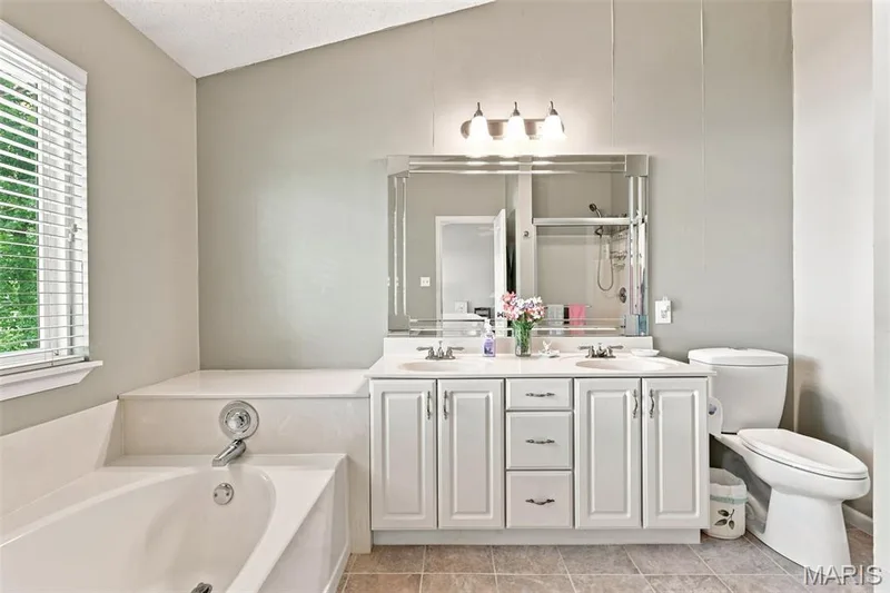 White dual-sink vanity with chrome faucets and built-in storage — 55 Treeshade Court, St Peters, MO 63376
