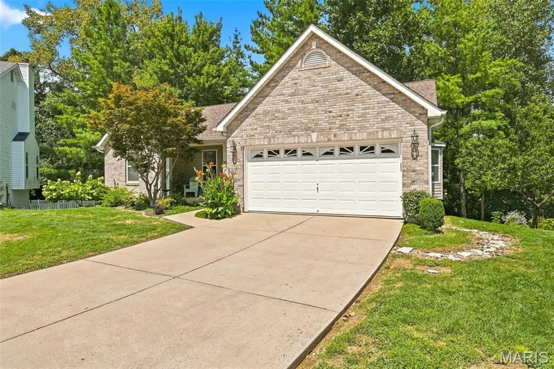 Brick and siding exterior featuring an attached two-car garage, concrete driveway, and established landscaping — 55 Treeshade Court, St Peters, MO 63376