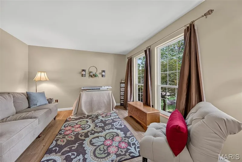 Bright living area featuring wood-finish flooring, two large windows with mullions, and neutral wall tones — 10 Docs Ct., St Charles, MO 63303