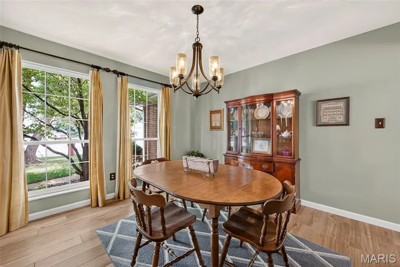 Dining area with wood-finish flooring, two large windows, a decorative chandelier, and crown molding — 10 Docs Ct., St Charles, MO 63303