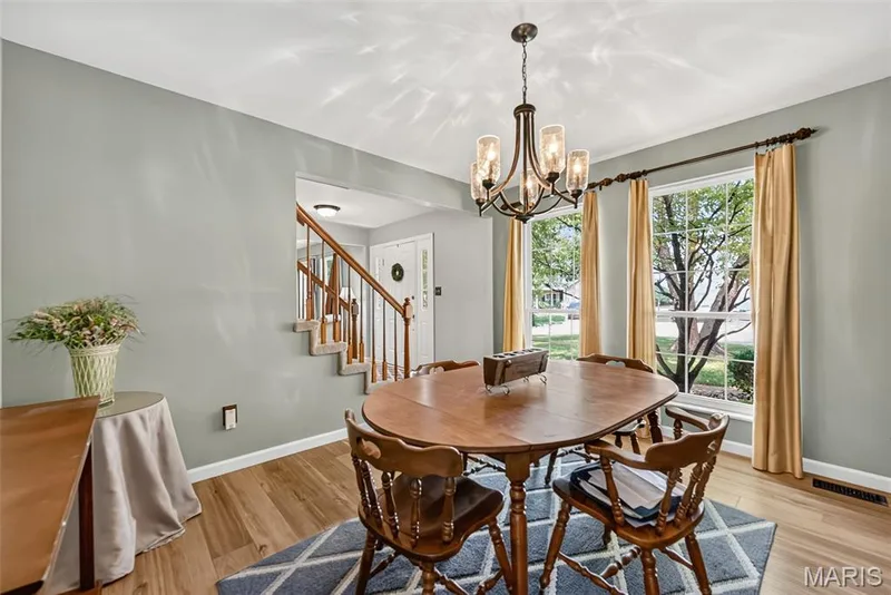 Wood-finish flooring, a decorative multi-light chandelier, and multiple windows with white trim — 10 Docs Ct., St Charles, MO 63303