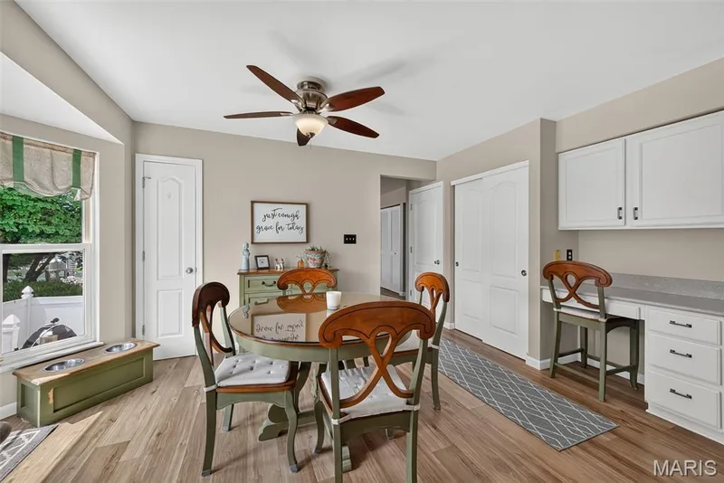 Wood-finish flooring, white paneled doors, ceiling fan with integrated lighting, built-in desk area with upper cabinetry, and a bay window — 10 Docs Ct., St Charles, MO 63303