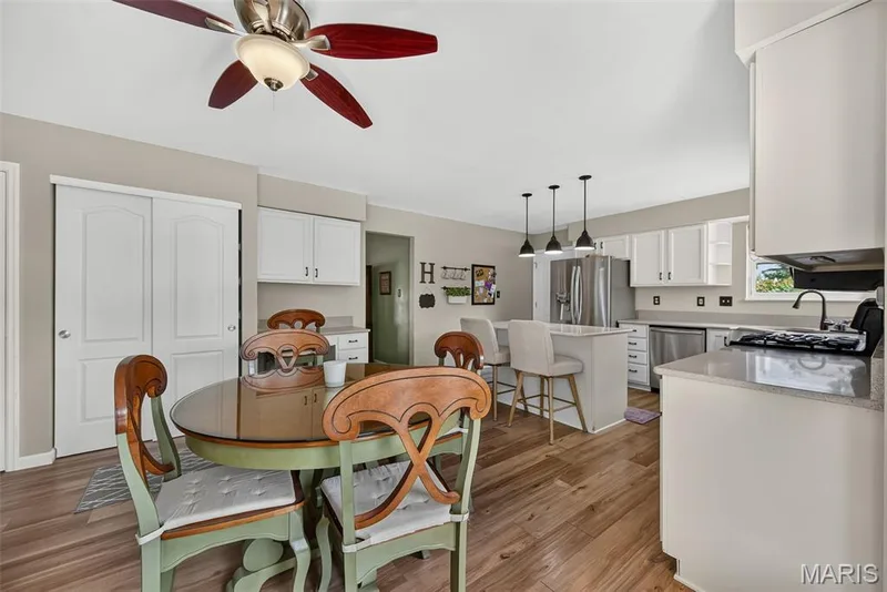 Kitchen featuring white cabinetry, stainless steel appliances, a center island with bar seating, and wood-finish flooring — 10 Docs Ct., St Charles, MO 63303