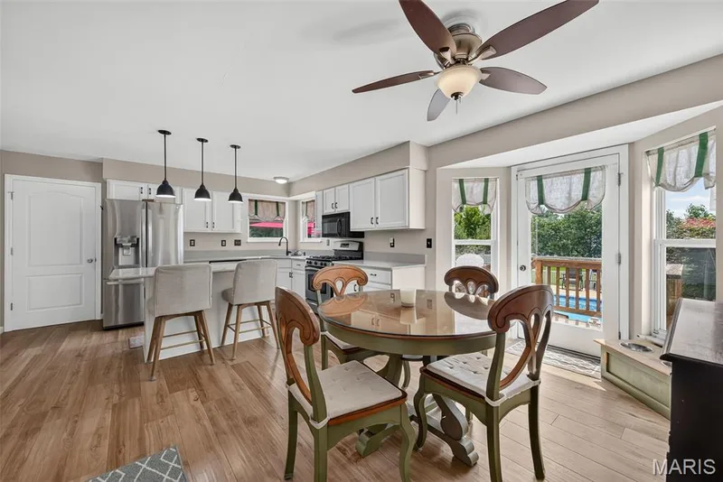 Hardwood-finish flooring, white cabinetry, stainless steel appliances, breakfast bar with pendant lighting, and a ceiling fan — 10 Docs Ct., St Charles, MO 63303
