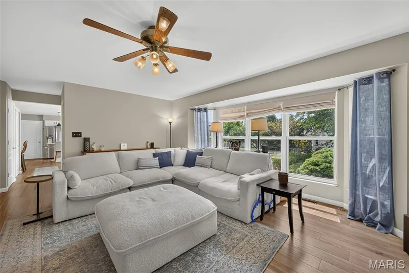 Warm wood-finish flooring, a ceiling fan with integrated lighting, and neutral wall tones create an inviting atmosphere — 10 Docs Ct., St Charles, MO 63303