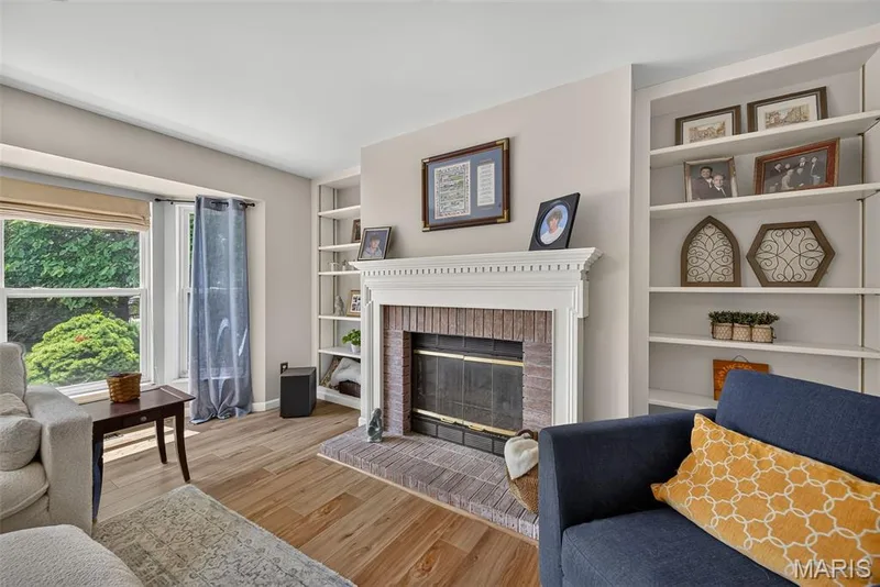 Wood-finish flooring, brick fireplace with mantel, built-in shelving, and large window — 10 Docs Ct., St Charles, MO 63303