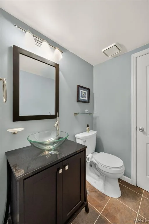 Dark wood-finish vanity with a vessel sink, dark countertop, and tiled flooring — 10 Docs Ct., St Charles, MO 63303