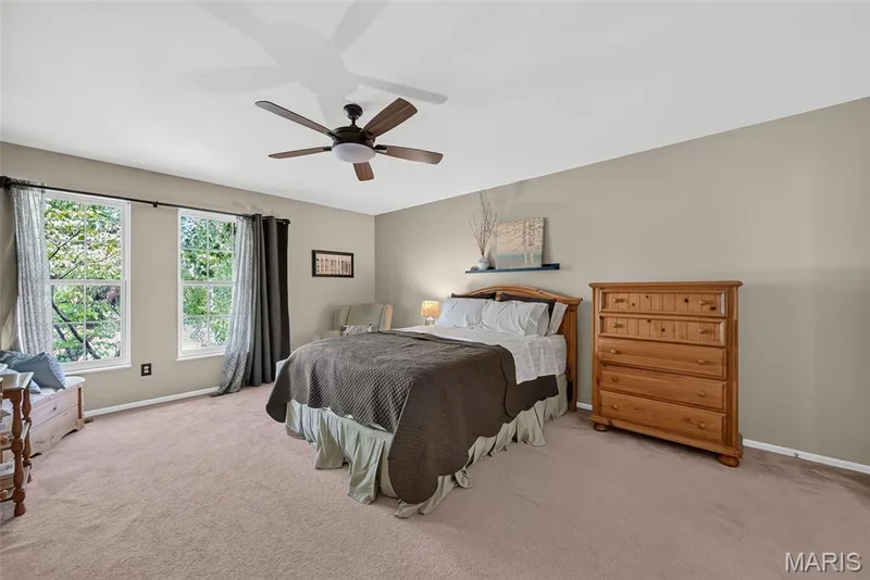 Carpeted room featuring a ceiling fan with integrated lighting, two windows, and a floating wall shelf — 10 Docs Ct., St Charles, MO 63303