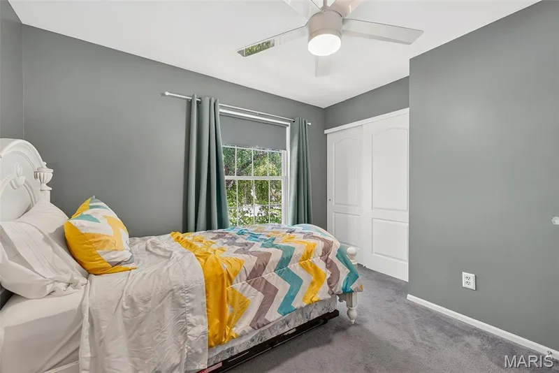 Ceiling fan with integrated lighting, window with drapes, sliding closet doors, gray wall finish, and gray carpeting — 10 Docs Ct., St Charles, MO 63303