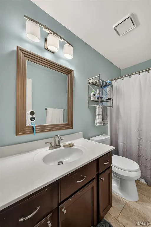 Vanity with integrated sink, brushed nickel faucet, framed mirror, and coordinating overhead lighting — 10 Docs Ct., St Charles, MO 63303