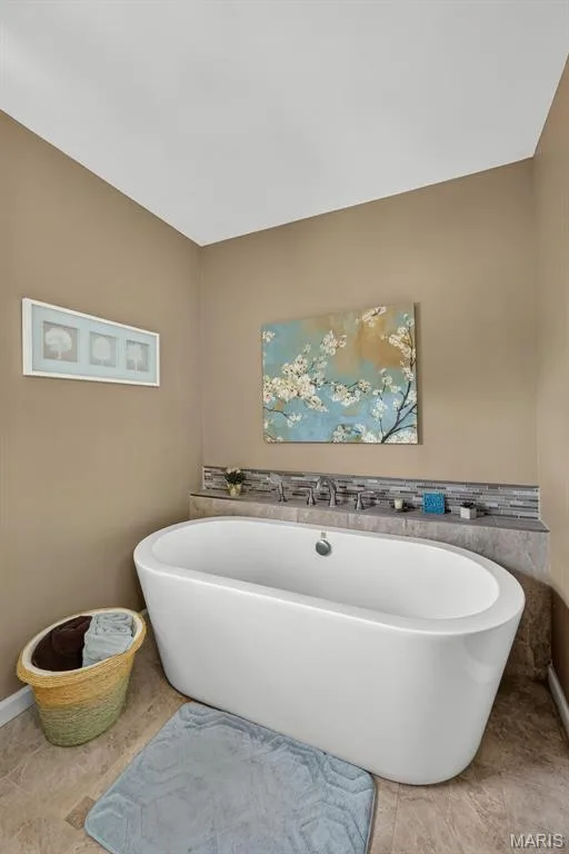 Freestanding soaking tub with chrome fixtures, set against a tiled backsplash and neutral wall tones — 10 Docs Ct., St Charles, MO 63303