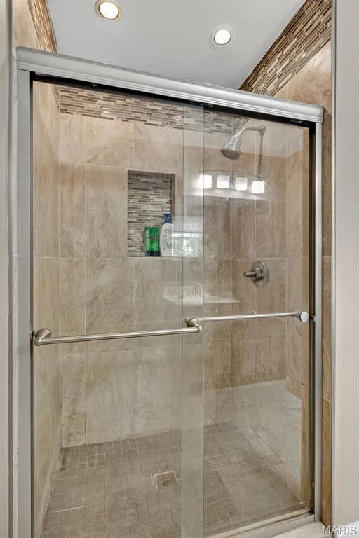 Tiled shower featuring a glass enclosure with brushed nickel hardware, a recessed niche, and mosaic tile accents — 10 Docs Ct., St Charles, MO 63303