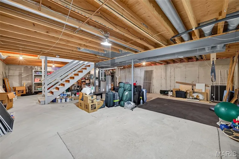 Unfinished concrete flooring, exposed wood joists, structural steel beam, and painted staircase with open risers — 10 Docs Ct., St Charles, MO 63303