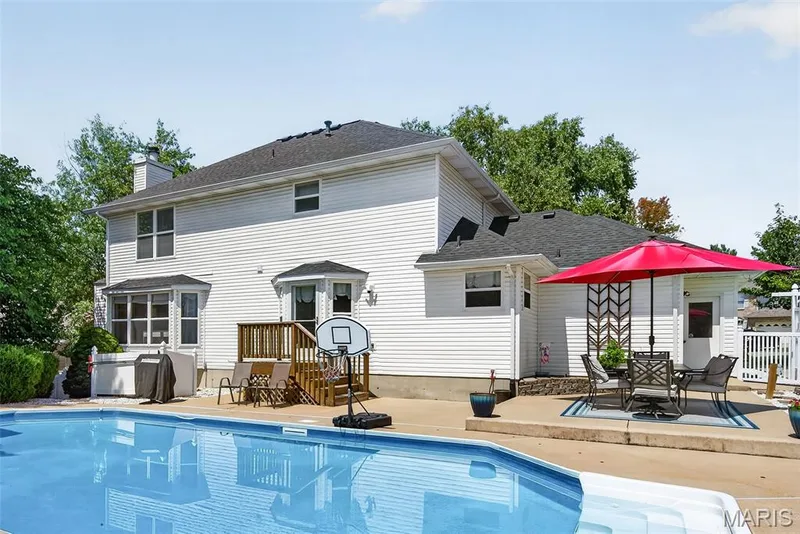 In-ground swimming pool, concrete pool deck, white vinyl siding, wood deck, and bay windows — 10 Docs Ct., St Charles, MO 63303