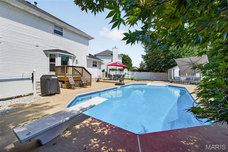 Expansive backyard with an in-ground swimming pool, concrete pool deck, and a wood deck — 10 Docs Ct., St Charles, MO 63303