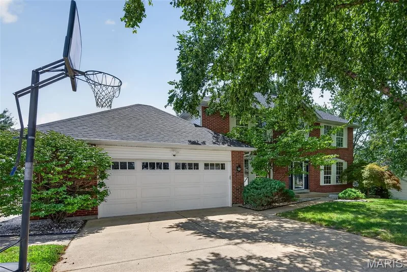 Brick facade residence featuring a two-car garage with panel doors, asphalt shingle roofing, and a concrete driveway — 10 Docs Ct., St Charles, MO 63303