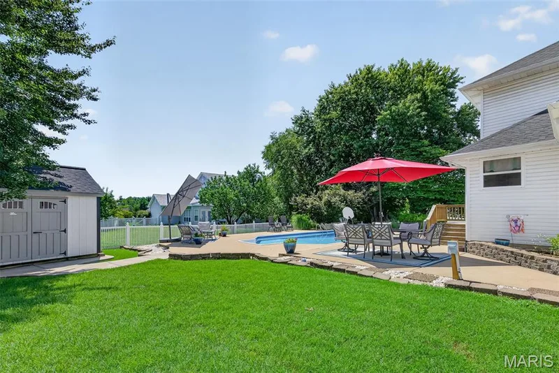 Expansive backyard featuring a manicured lawn, an in-ground swimming pool, and a white picket fence — 10 Docs Ct., St Charles, MO 63303