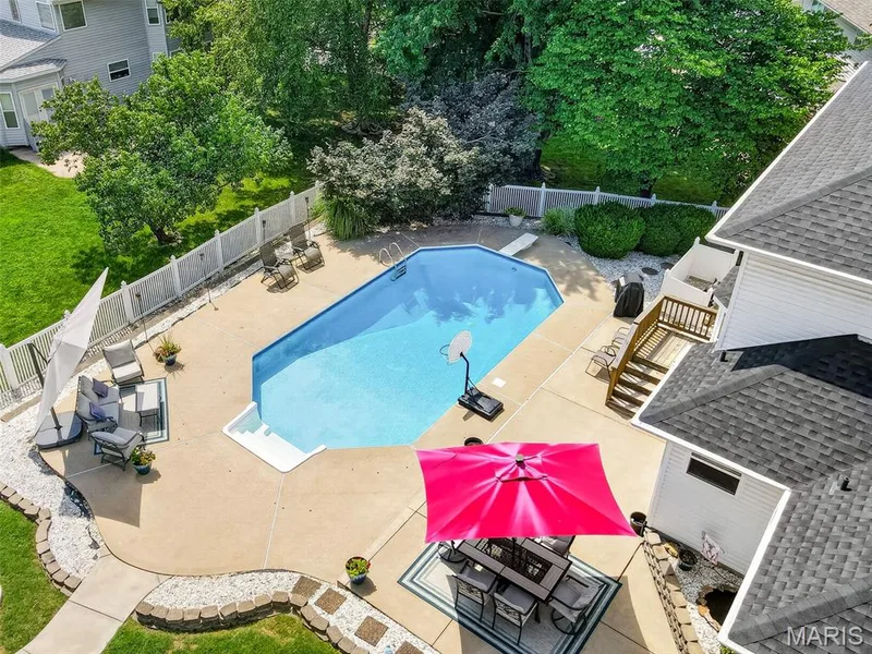 In-ground swimming pool with a concrete surround, white picket fencing, and a multi-level wood deck — 10 Docs Ct., St Charles, MO 63303