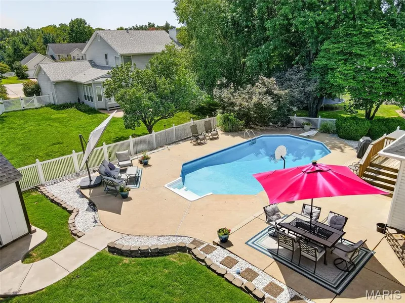 Expansive backyard featuring a concrete patio, in-ground swimming pool, and mature trees — 10 Docs Ct., St Charles, MO 63303
