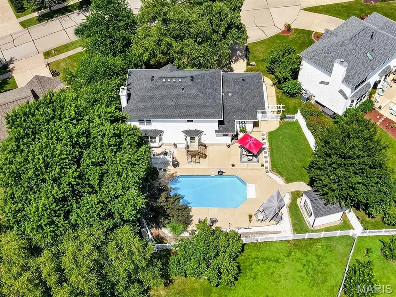 Exterior featuring a private pool, extensive concrete patio, white picket fence, a detached shed, and mature trees — 10 Docs Ct., St Charles, MO 63303