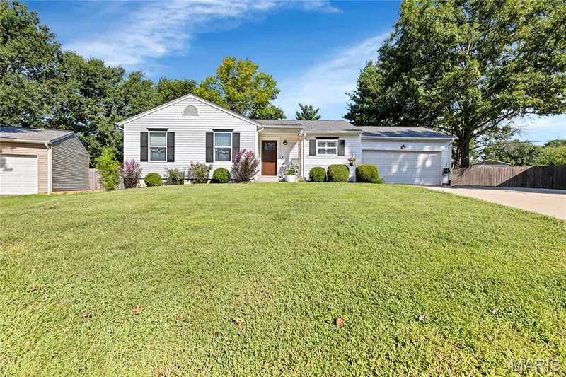 Single-story residence featuring white siding, a single-car garage, and a separate detached garage structure — 601 Big Timber Lane, O'Fallon, MO 63368