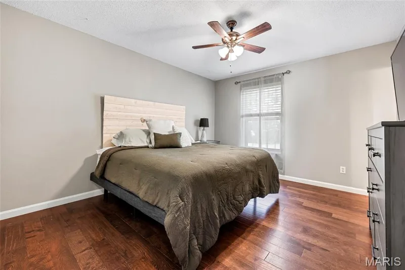 Rich wood floors, a classic ceiling fan, and tailored blinds complete this bright, open room—with plenty of space to comfortably fit a larger bed, nursery setup, or full office suite. — 601 Big Timber Lane, O'Fallon, MO 63368