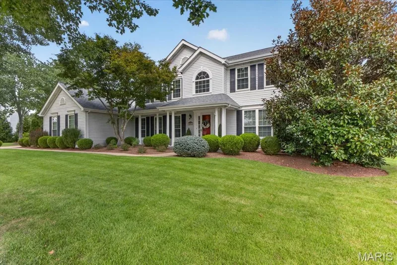 Two-story residence with light-colored siding, black window shutters, and a covered front porch featuring white columns — 5856 Canterfield Court, Weldon Spring, MO 63304