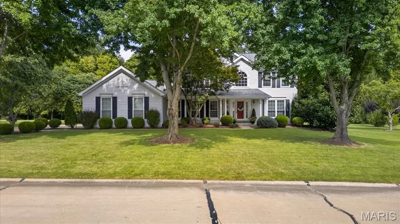 Two-story residence with siding exterior, mature trees, manicured lawn, and a covered front entry — 5856 Canterfield Court, Weldon Spring, MO 63304