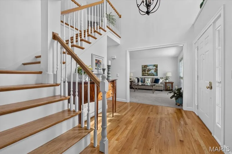 Hardwood flooring, two-story entryway, grand staircase with wood newel and balusters, transom window, recessed doorway — 5856 Canterfield Court, Weldon Spring, MO 63304