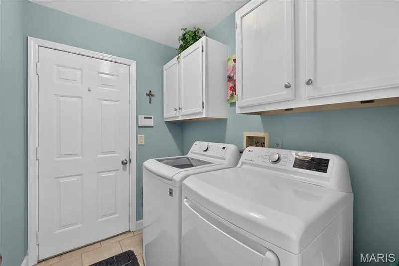 Laundry area with light blue wall color, white upper cabinetry, and tile flooring — 5856 Canterfield Court, Weldon Spring, MO 63304