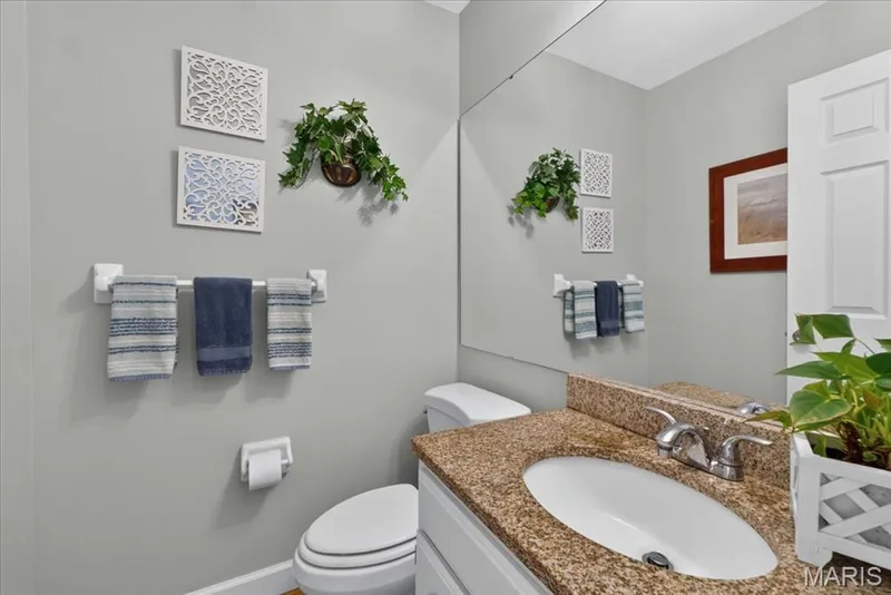 Vanity with granite countertop and integrated sink, chrome faucet, wall-mounted mirror, and white panel door — 5856 Canterfield Court, Weldon Spring, MO 63304