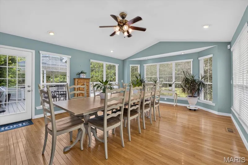 Vaulted ceiling with recessed lighting and ceiling fan, wood-finish flooring, multiple windows, and a glass-paneled door — 5856 Canterfield Court, Weldon Spring, MO 63304