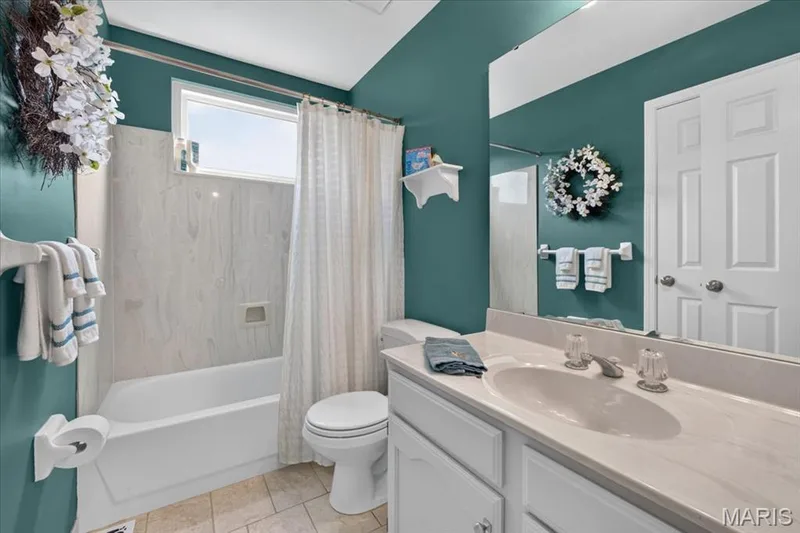 Bathroom featuring a full vanity with an integrated sink, a built-in bathtub with a shower, a horizontal window, and panel doors — 5856 Canterfield Court, Weldon Spring, MO 63304