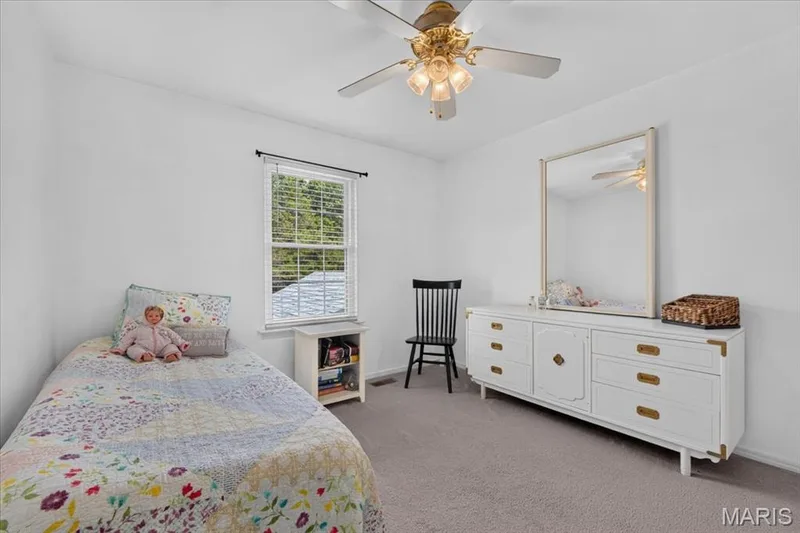 Bright room featuring a window with blinds, a ceiling fan with light fixture, and neutral carpeting — 5856 Canterfield Court, Weldon Spring, MO 63304