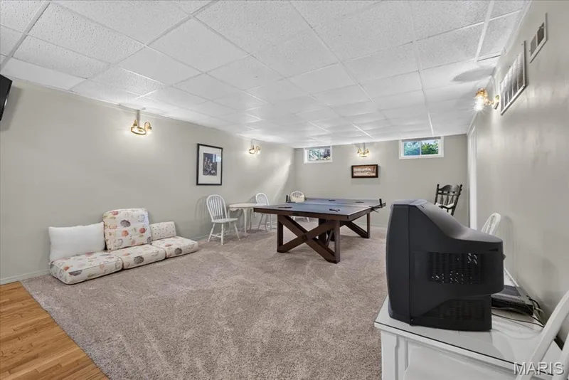 Finished space with light gray wall paint, wall-mounted light fixtures, textured ceiling tiles, and light-colored carpet — 5856 Canterfield Court, Weldon Spring, MO 63304