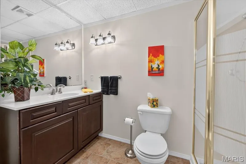 Bathroom featuring a vanity with dark wood-finish cabinetry, a white countertop, and a large mirror — 5856 Canterfield Court, Weldon Spring, MO 63304