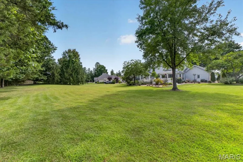 Expansive green lawn with mature trees and a traditional-style residence — 5856 Canterfield Court, Weldon Spring, MO 63304