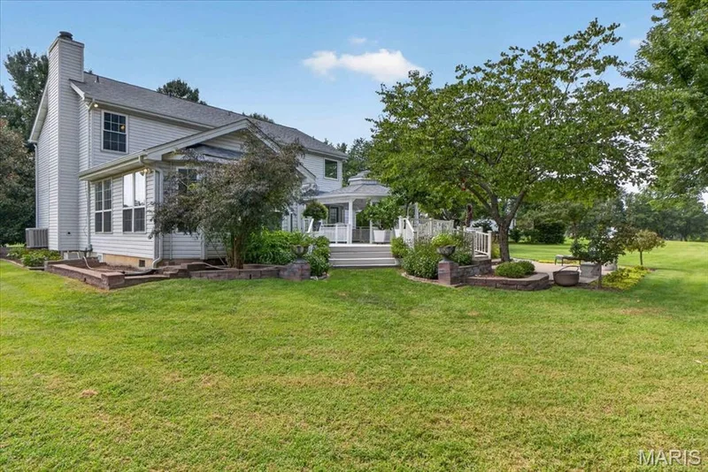 Expansive grassy lawn complemented by a spacious deck, white gazebo, and mature trees — 5856 Canterfield Court, Weldon Spring, MO 63304