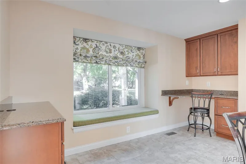 Built-in window seat with a cushioned surface, wood cabinetry with stone countertops, and a built-in desk area — 2508 Peppermill Lake Court, Chesterfield, MO 63005