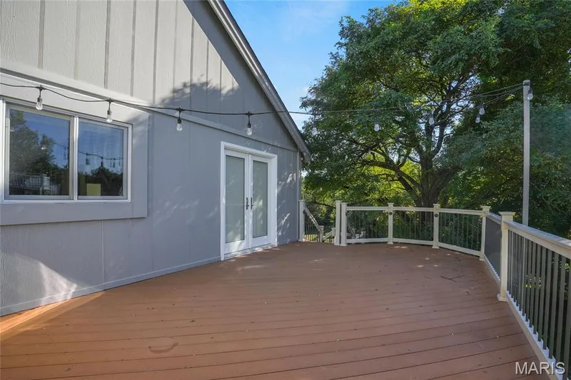 Expansive outdoor deck with wood-finish flooring, white railing, and dual glass panel doors — 2508 Peppermill Lake Court, Chesterfield, MO 63005